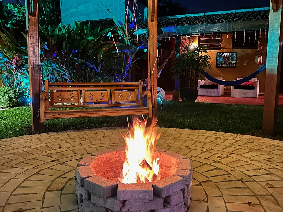 Fire pit aceso à noite no jardim da Pousada Point Beach Jambolões